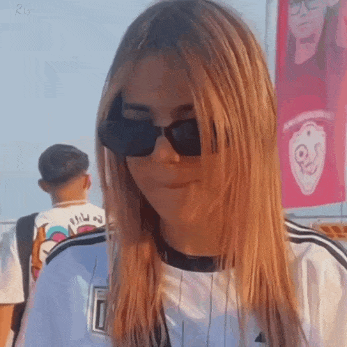 a woman wearing sunglasses and a white shirt is making a face .