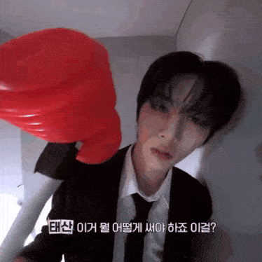 a man in a suit is holding a red boxing glove