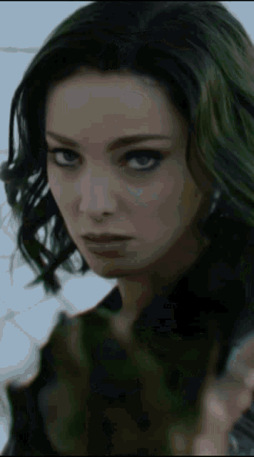 a close up of a woman with green hair looking at the camera