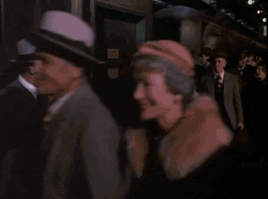 a man in a suit and hat is standing in a crowd of people