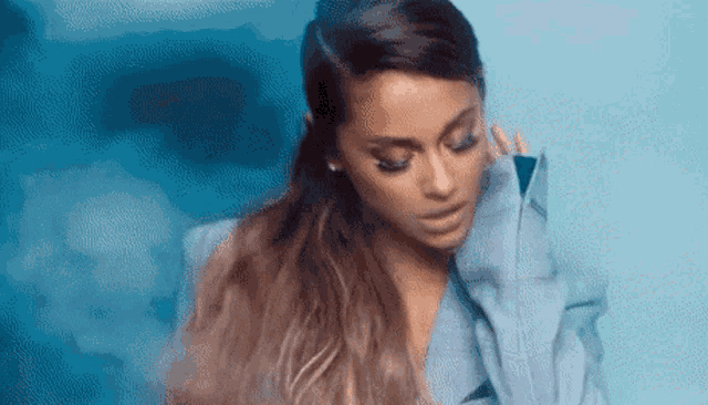 ariana grande is wearing a blue jacket and a blue background .