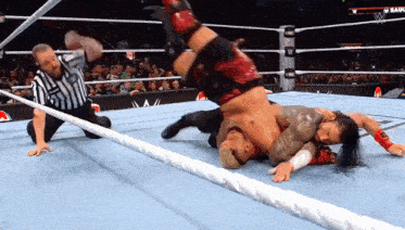 a referee watches a wrestling match between two wrestlers