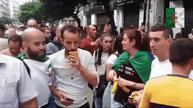 a crowd of people are gathered in front of a building with a flag that says algeria