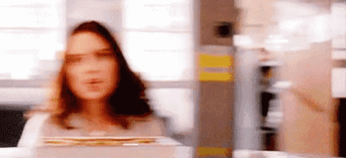 a blurry picture of a woman standing in a room holding a box .