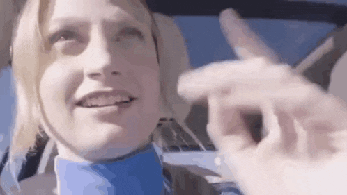 a woman is sitting in the driver 's seat of a car and giving a thumbs up .
