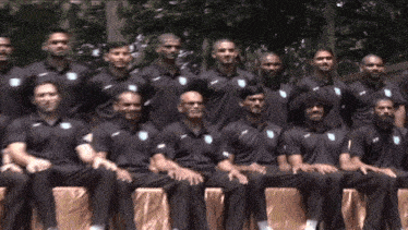 a group of men are posing for a picture and they are wearing black shirts