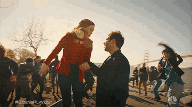 a man and a woman are holding hands in front of a crowd and the hashtag #zoeysplaylist is visible