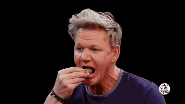 a man in a purple shirt holds a piece of food