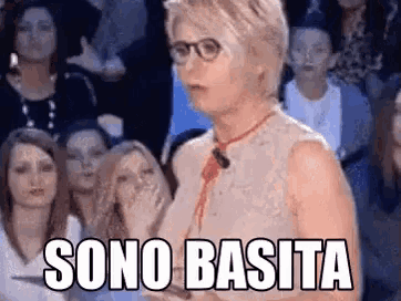 a woman wearing glasses and a red tie is standing in front of a crowd of people and saying sono basita .