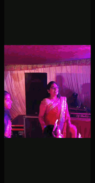 a woman in a red saree is standing in front of a dj mixer