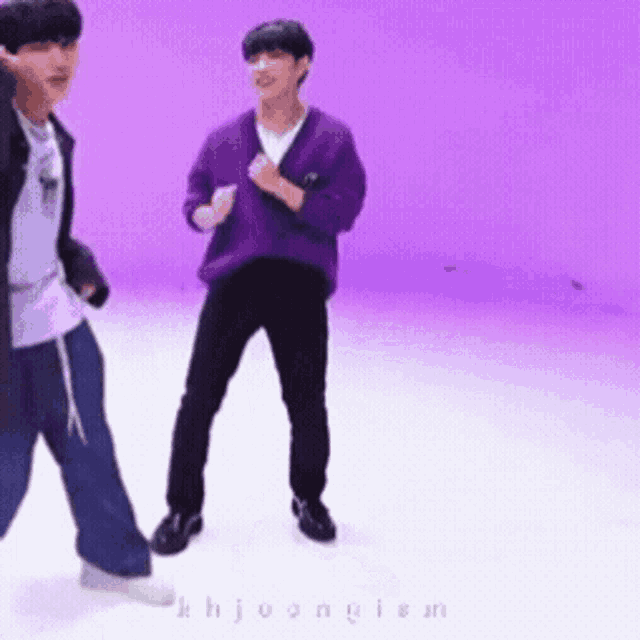a man in a purple sweater is dancing with another man in a black jacket .