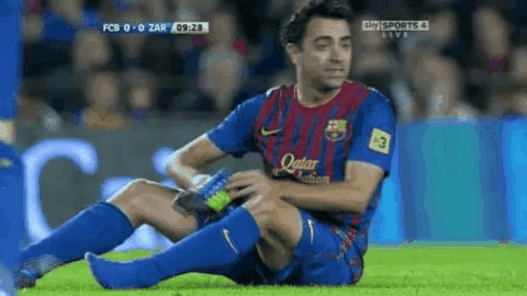 a soccer player is sitting on the field with his knee in pain