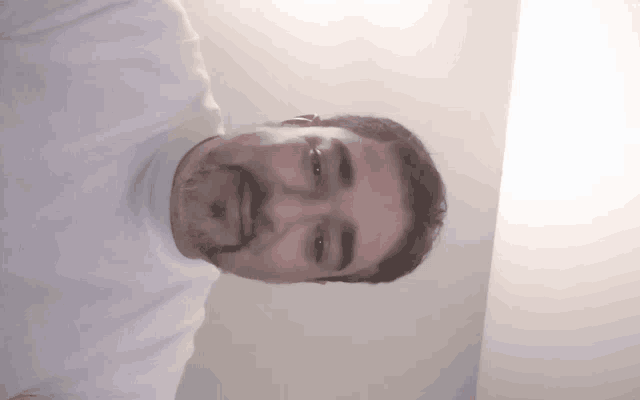 a man with a beard is wearing a white shirt and smiling