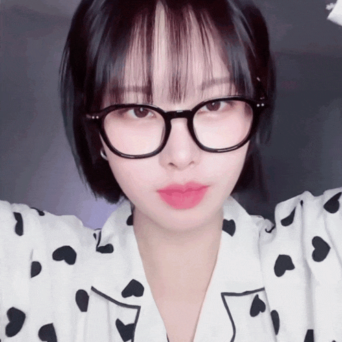 a woman wearing glasses and a polka dot shirt looks at the camera