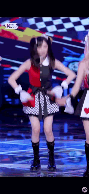 a woman in a red and black dress is dancing on a stage with two other women .