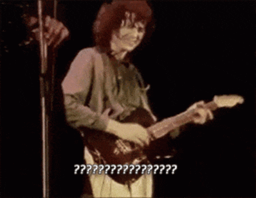 a man is playing a guitar in front of a microphone with the words " ?? " written on the bottom of the image