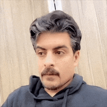 a man with gray hair and a mustache is wearing a black hoodie