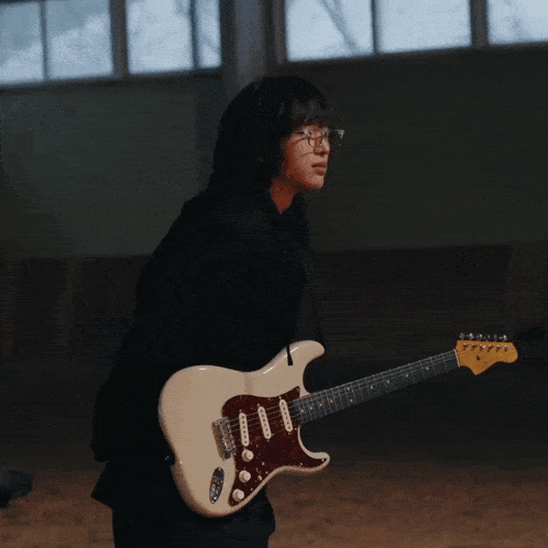 a woman holding a white electric guitar with a fender logo on it