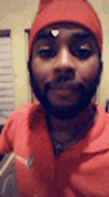 a man with a beard wearing a red hat and a red jacket is smiling .