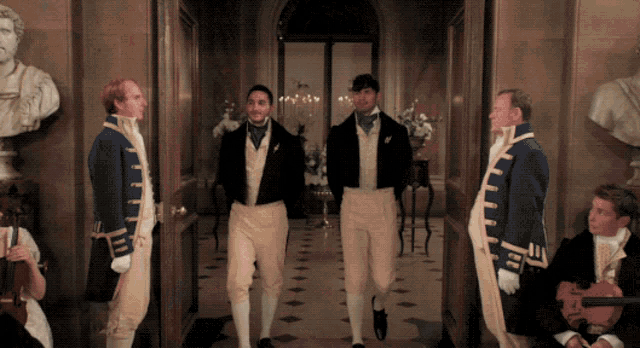 a group of men standing in a hallway with one wearing a blue jacket