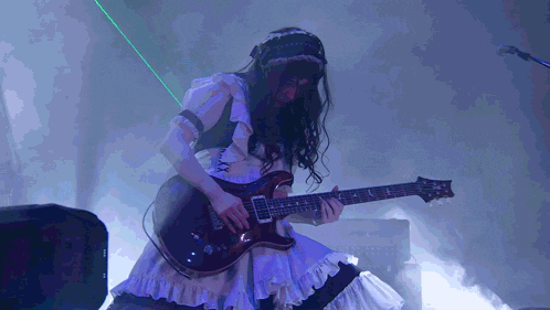 a woman in a maid costume is playing a guitar