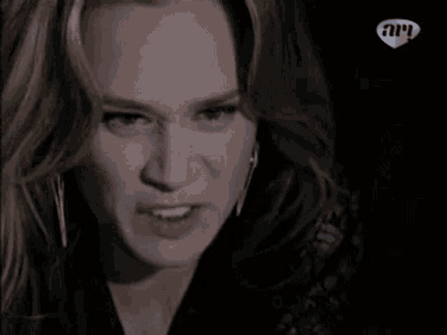 a woman is holding a bloody knife in front of her face with a heart in the lower right corner