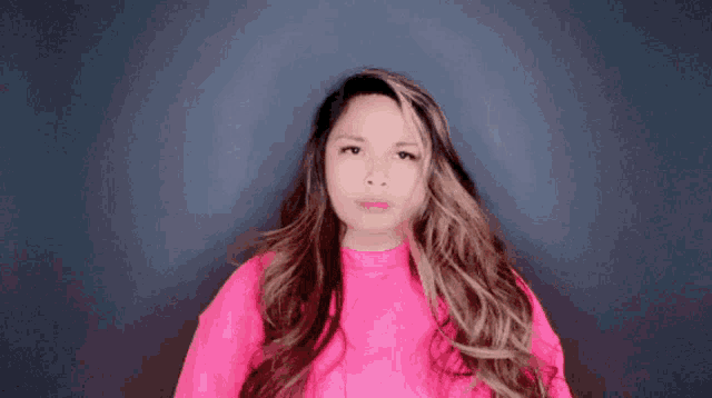 a woman with long hair wearing a pink sweater