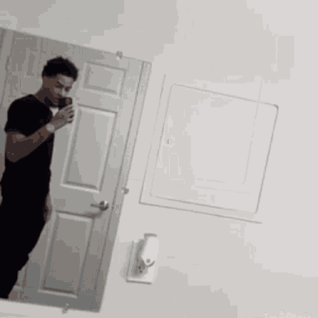 a man is taking a selfie in front of a mirror .