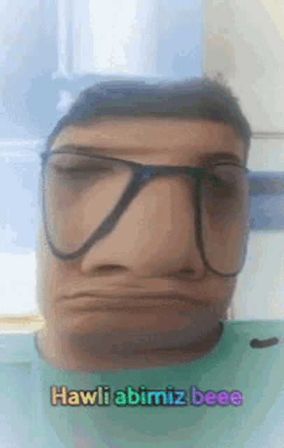 a man wearing glasses has hawli abimiz beee written on the bottom