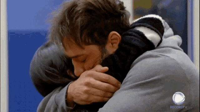 a man is hugging a woman in front of a recordtv logo
