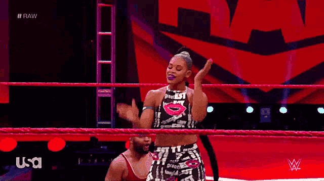 a woman is dancing in a wrestling ring while wearing a top that says greatest
