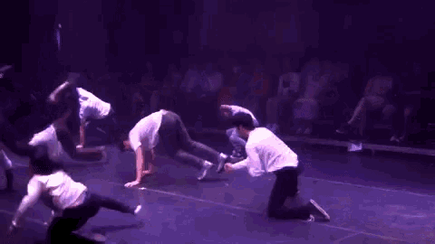 a group of people doing handstands on a stage in front of a crowd