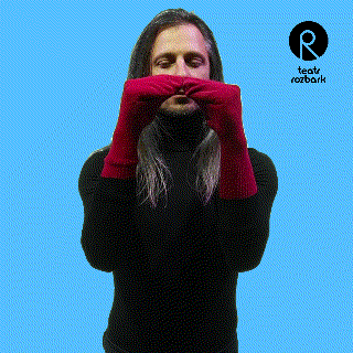a man wearing a black turtleneck and red gloves with a logo for teatr rozbark behind him