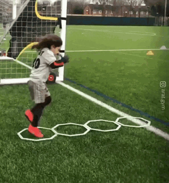 a little girl wearing a number 10 jersey is jumping over a maze
