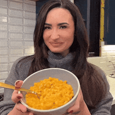 a woman holding a bowl of macaroni and cheese