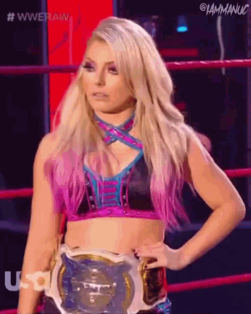 a woman is standing in a wrestling ring wearing a championship belt .