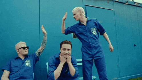 three men wearing blue overalls with a sticker that says crew on it