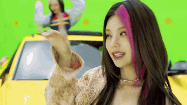 a girl with pink hair is standing next to a yellow car .
