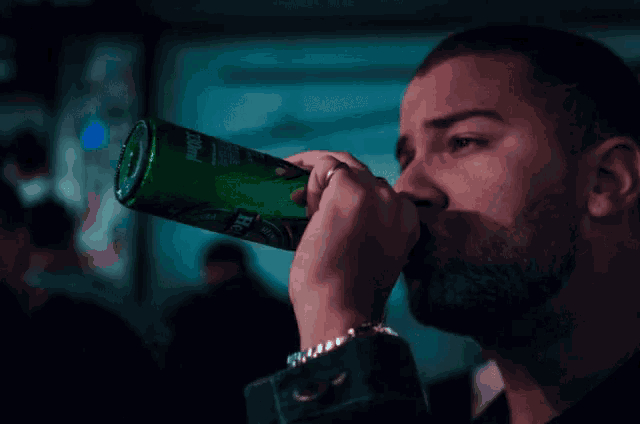 a man drinking from a green bottle that says heineken