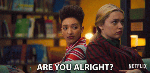two girls are sitting back to back and one of them is asking the other if she is alright