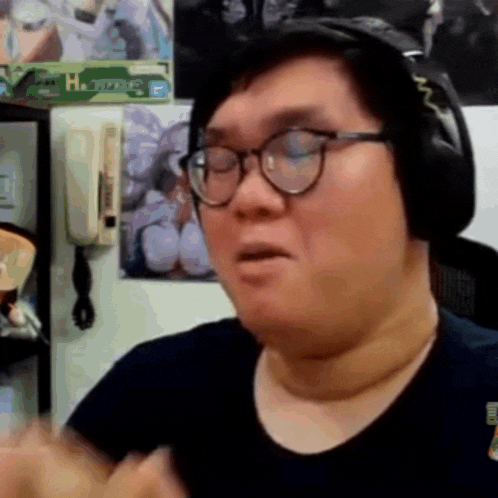 a man wearing glasses and headphones is sitting in front of a wall with a picture of a woman on it