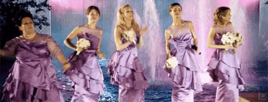 a group of bridesmaids in purple dresses are dancing in front of a fountain