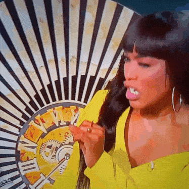 a woman in a yellow shirt is playing a game with a fan that has roman numerals