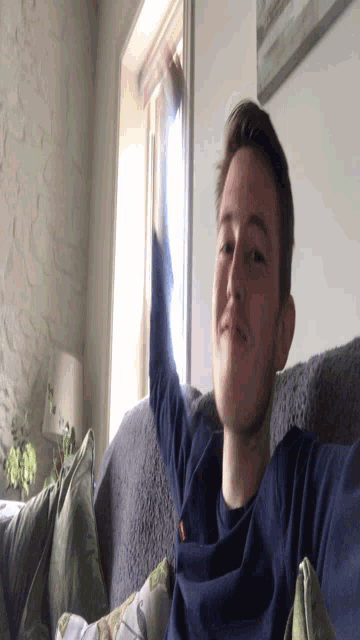 a man in a blue shirt is laying on a couch in a living room