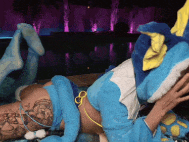 a woman in a blue and yellow costume is laying down