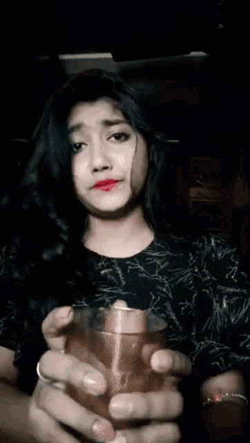 a woman in a black shirt is holding a silver object