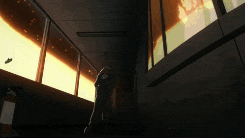 a person standing in a hallway looking out a window at a fire
