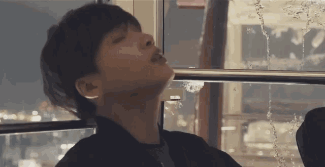 a young man is sitting on a ferris wheel with his eyes closed and his mouth open .