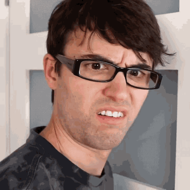 a man wearing glasses makes a funny face with his mouth open
