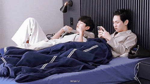 two men laying on a bed with the word almighty on the bottom left